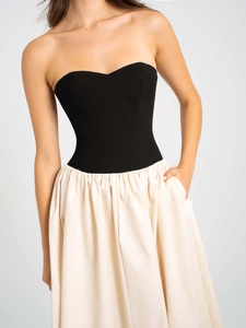 Détail de robe bustier élégante avec haut noir et jupe plissée de couleur crème