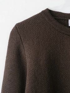 Détail du col en tricot côtelé d'un pull marron foncé avec une texture épaisse de qualité