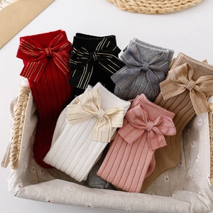 Detail of baby knee high socks with gold-ribbon bows in six assorted colors in a basket