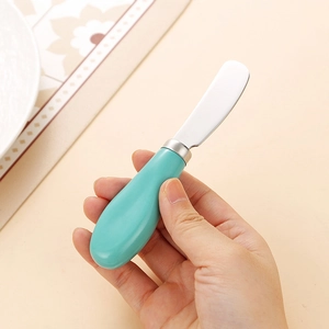 Primo piano di un coltello da burro con manico in ceramica verde e lama in acciaio