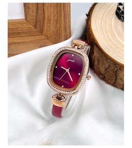 Détail de la montre à quartz ovale bordeaux avec lunette en strass rose doré et bracelet rouge