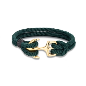 Macro view of a gold anchor clasp on dark green woven nautical bracelet