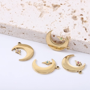 Golden moon and star pendants with colored crystals on marble background for DIY jewelry