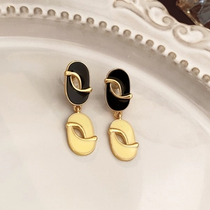 Close-up of vintage flower earrings with black and cream oval enamel on a white plate