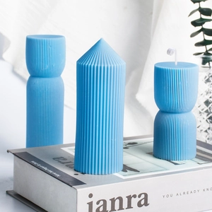 Bougies géométriques bleues à rayures verticales sur des livres modernes blancs en décor
