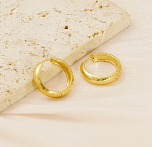 Close-up of elegant 18K gold plated stainless steel hoop earrings on a stone base