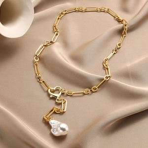 Close-up of golden paperclip chain with heart clasp and large baroque pearl pendant