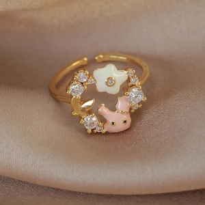 Detail of gold floral ring with pink rabbit, white flower and sparkling cubic zirconia