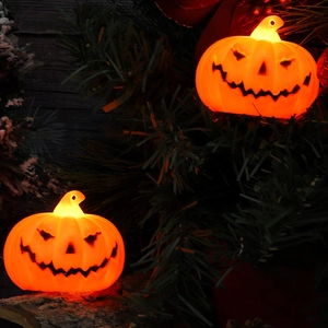 Macro detail of a glowing orange LED pumpkin lantern set amidst dark pine branches