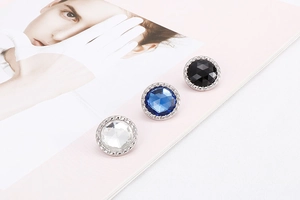 Macro detail of round cut crystal earrings in black, blue and white with silver base