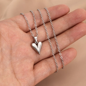 Polished silver heart pendant necklace on an O-chain held in palm for scale