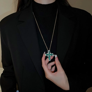 Vue détaillée du pendentif croix en émeraude verte et diamants sur chaîne dorée