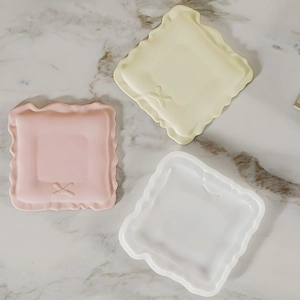 Detailed view of wavy square resin trays in pink, yellow and white with bow relief
