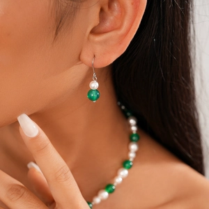 Detail of beaded necklace and earrings set featuring white pearls and green agate beads