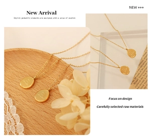 Detailed view of an oval 18K gold plated pendant with engraving on a fine link chain