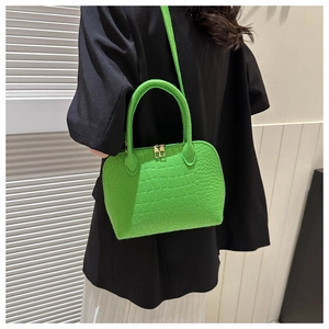 Detail of bright green shell bag showing crocodile texture and gold dual zippers