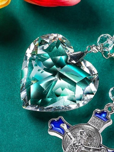 Detailed macro view of heart crystal and silver enamel cross pendant for car mirror