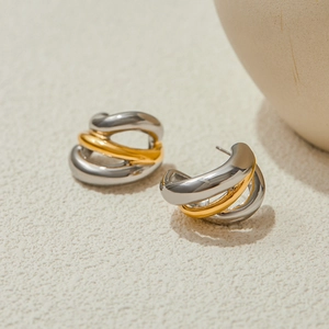 Detailed view of C-shaped earrings with gold and silver layered twisted design