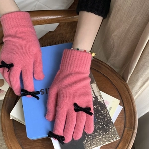 Pink knitted gloves for women featuring black bow decoration and touchscreen capability