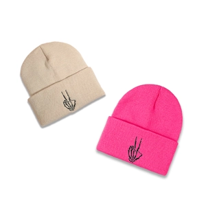 Winter knitted beanies in beige and bright pink with embroidered skeleton hand gesture
