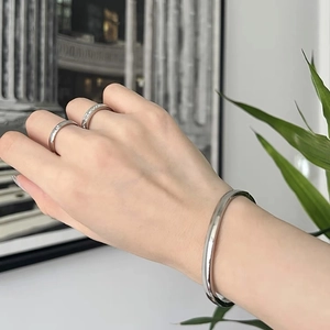 Set bracciale in acciaio al titanio lucido e anelli d'argento indossati a mano