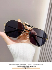 Detailansicht der geometrischen goldenen Sonnenbrille mit dunklen Gläsern in der Hand