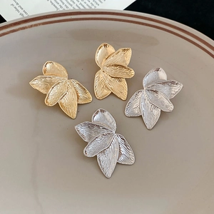 Detailed view of gold and silver petal-shaped earrings on a ceramic plate