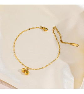 Detail of gold-plated stainless steel bracelet with polished round beads on satin background