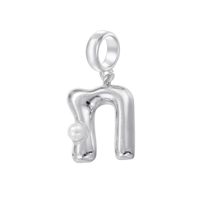 Détail macro du pendentif lettre N argenté avec incrustation de perle blanche sur fond blanc