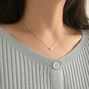 Close-up of minimalist sterling silver heart necklace worn on model neck