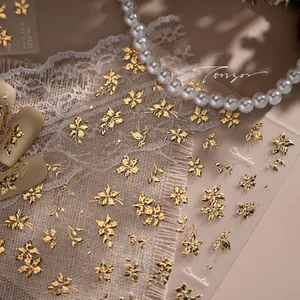 Macro detail of gold floral nail stickers with embossed vintage metallic flower pattern