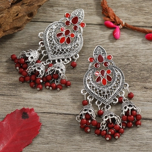 Bohemian retro tassel earrings with red enamel and bells on a vintage wood background