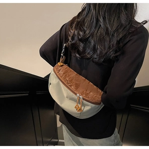 Detail of cross-body chest bag featuring dual zippers and adjustable buckle strap