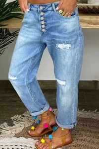 Détail du jean bleu clair avec braguette à boutons et genou déchiré tendance
