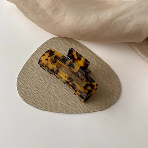 Detailed macro view of an amber leopard print acetate hair claw on a silk beige fabric