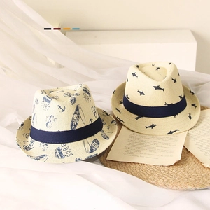 Detail view of kids straw hats featuring surf and shark prints with navy grosgrain ribbon