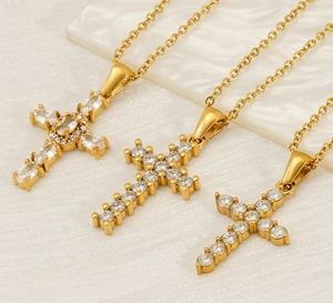 Detailed close-up of three gold cross necklaces with sparkling white zircon inlays