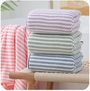 Detail of stacked coral fleece towels with wavy texture in pink, blue, and green hues