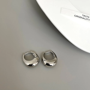 Macro shot of silver teardrop hoop earrings with polished metallic mirror finish