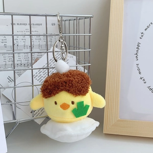 Close-up of yellow plush bird keychain with brown curly hair and metal clasp details