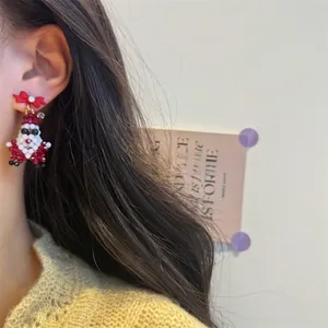 Close-up of handmade beaded Santa Claus earring with a red bow and white pearl detail