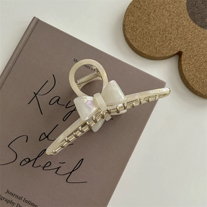 Dettaglio di una molletta per capelli a fiocco bianco perla su un libro estetico