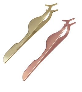 Detailed view of two professional metal eyelash applicators in gold and rose gold finishes