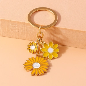 Detailed macro of yellow and white enamel daisy charms on a gold-tone metal keyring