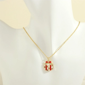 Detailed close-up of a Christmas gift box pendant with red enamel bow on a gold necklace