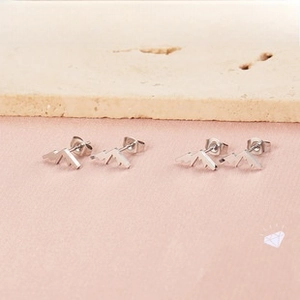 Detailed view of minimalist silver mountain geometric stud earrings on stone background