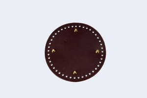 Macro detail of round DIY bag base in dark burgundy PU leather with four gold metal studs