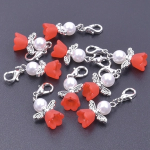 Close-up of heart angel wing charms with red tulip caps and pearls on dark background