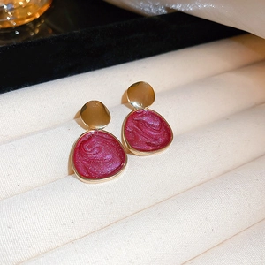 Detailed close-up of vintage gold frame earrings with dark red glitter resin finish