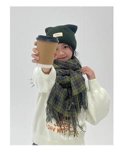 Close-up of green and blue plaid fringed scarf with matching cat-ear knitted hat